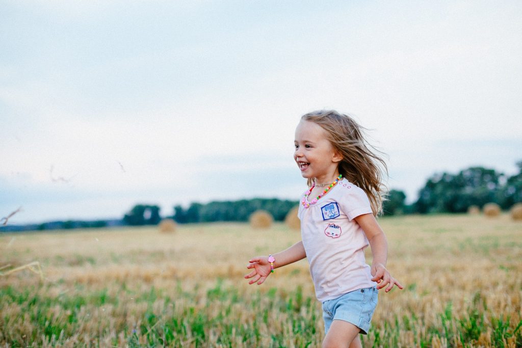 Smiling Girl Runs in an open green field